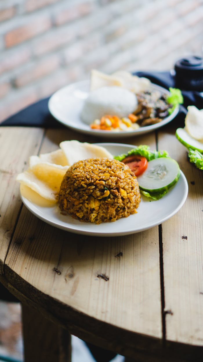 Mouth-watering nasi goreng with crisp vegetables and crackers on a wooden table.