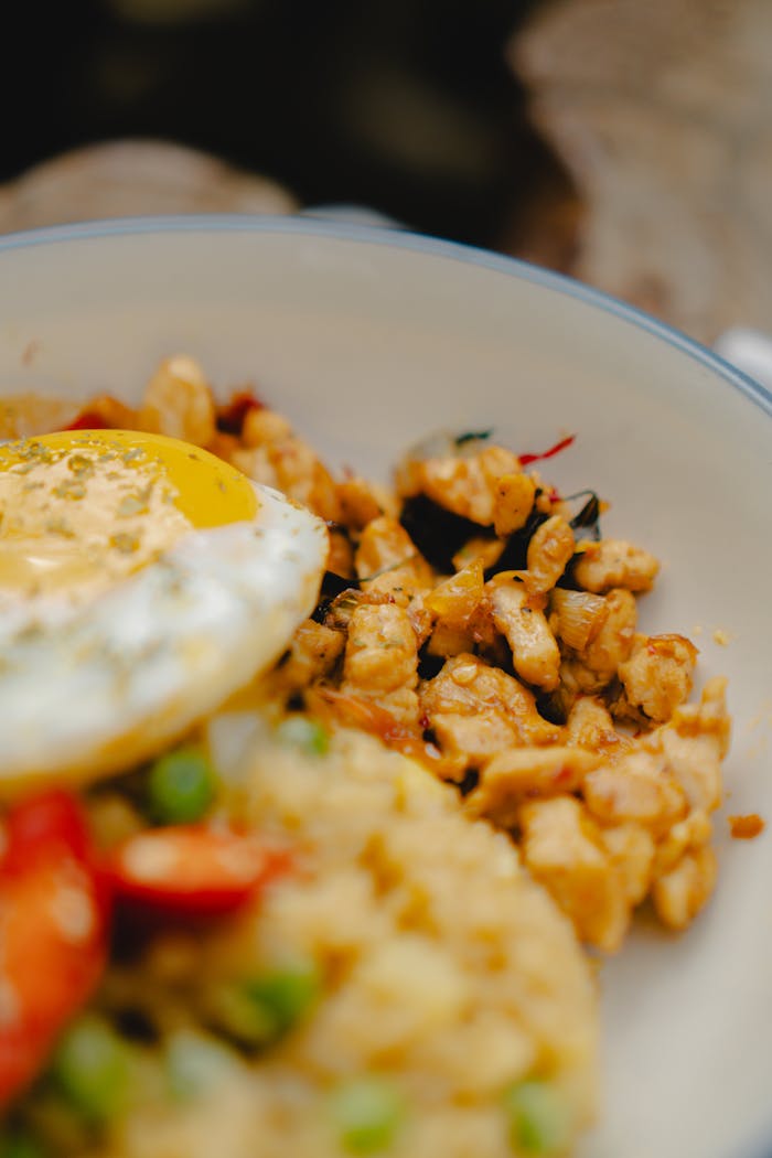 Close-up of nasi goreng with fried egg and spicy chicken, capturing Indonesian culinary essence.