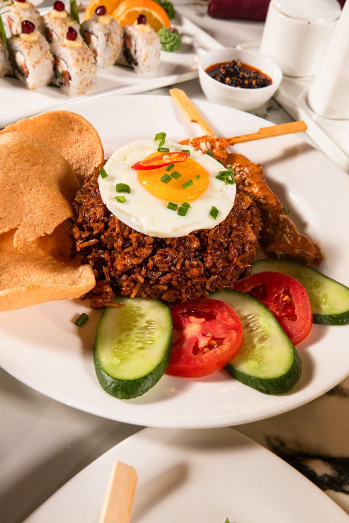 Indulge in a plate of Nasi Goreng with satay and fresh vegetables, perfect for food photography enthusiasts.