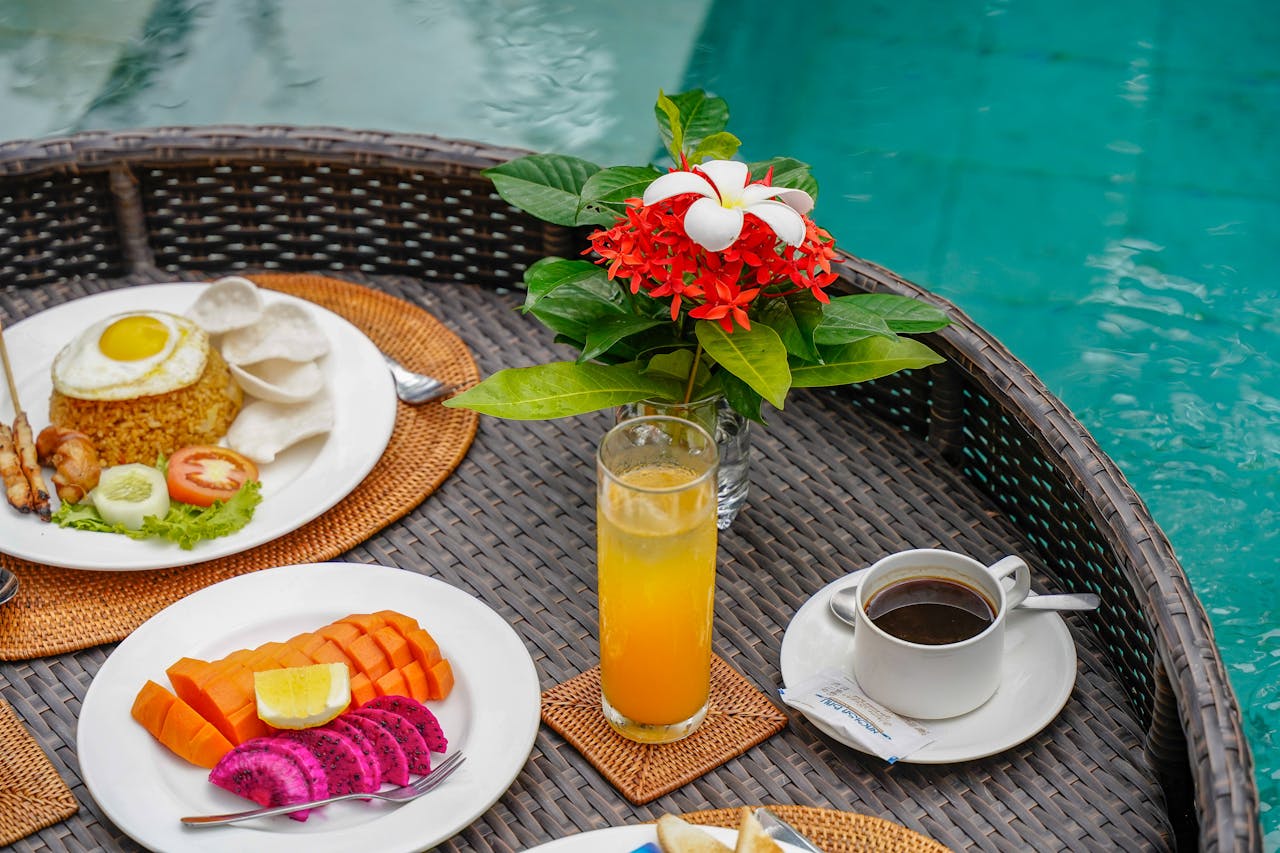 A vibrant poolside breakfast in Bali with tropical fruits, rice dish, and fresh coffee.