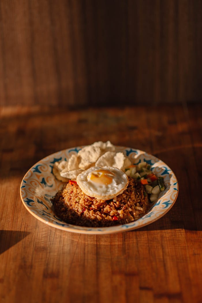 Appetizing plate of Indonesian fried rice served with a sunny-side-up egg and crackers.